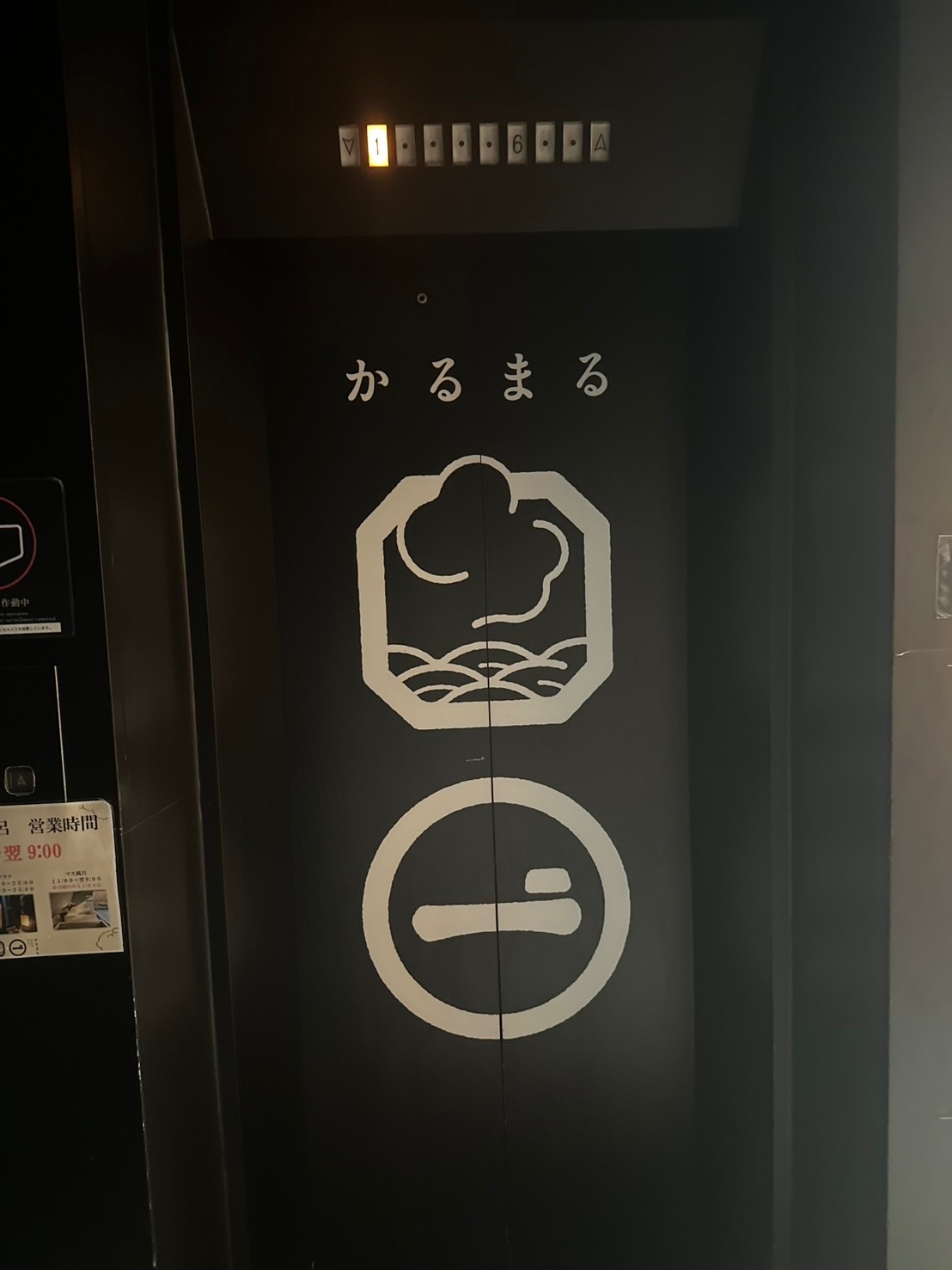 かるまるの名前とロゴが描かれた黒いエレベーターの扉